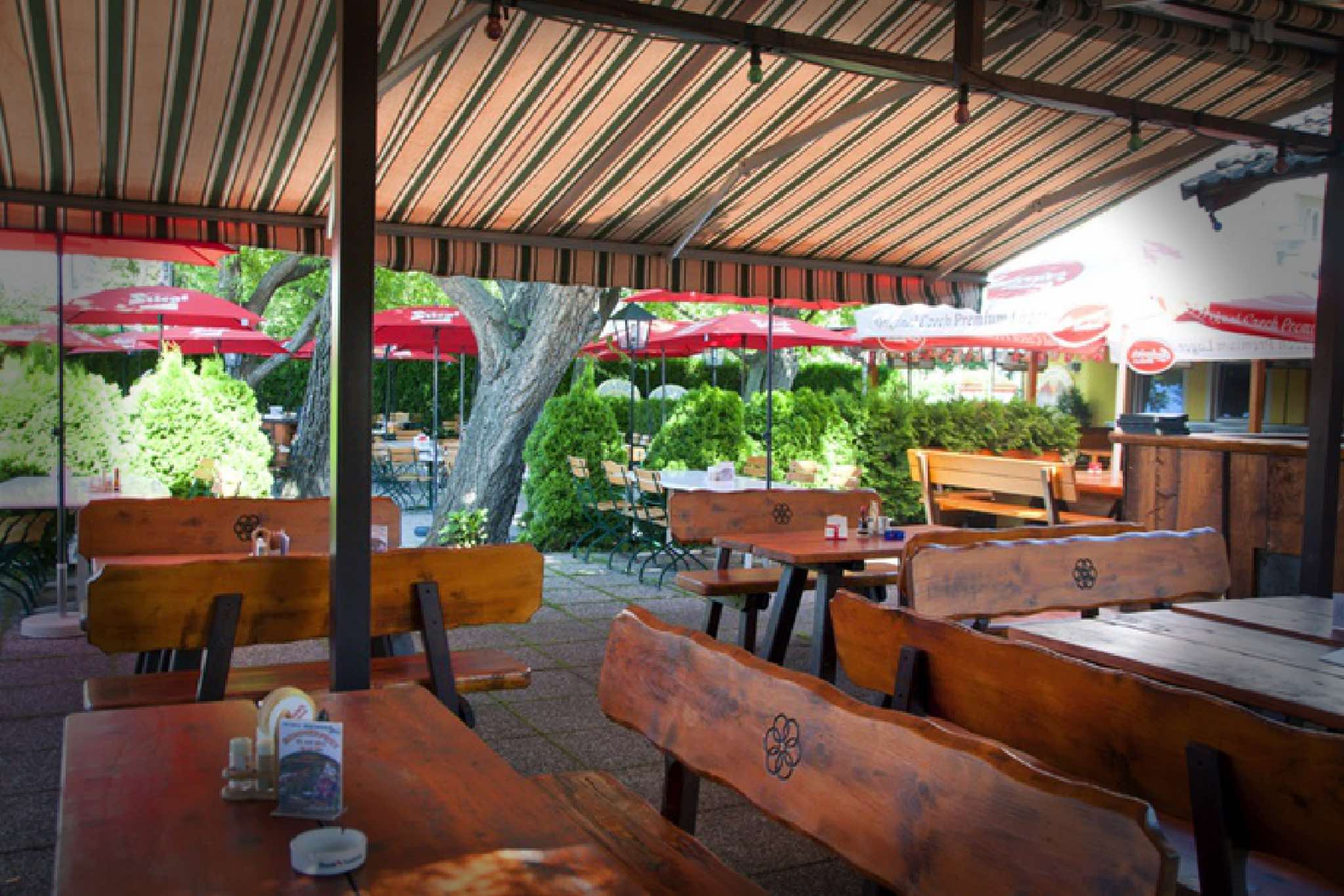 Überdachte Gartenterrasse mit rustikalen Holztischen